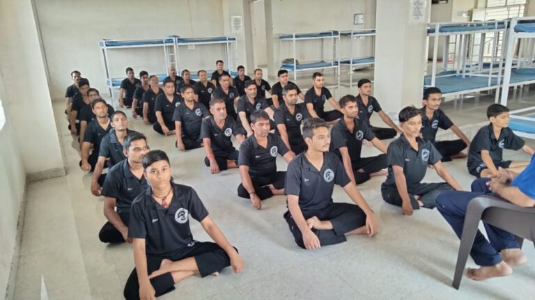 Recovery program participants listening to a counselor during a structured rehabilitation meeting in a hostel-style facility.